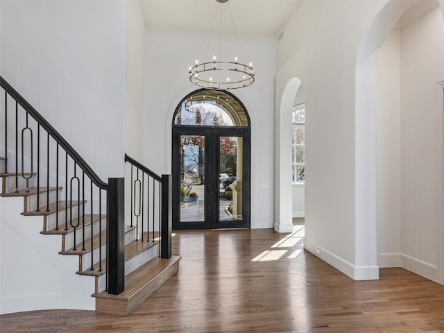 foyer with dark hardwood / wood-style flooring, french doors, a high ceiling, and an inviting chandelier