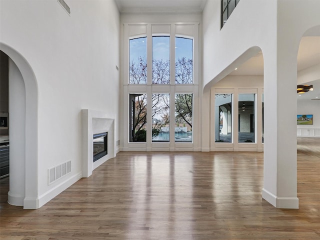 unfurnished living room with hardwood / wood-style floors, a towering ceiling, and ceiling fan