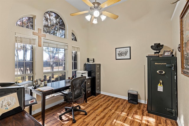 office space featuring hardwood / wood-style floors, ceiling fan, and a towering ceiling