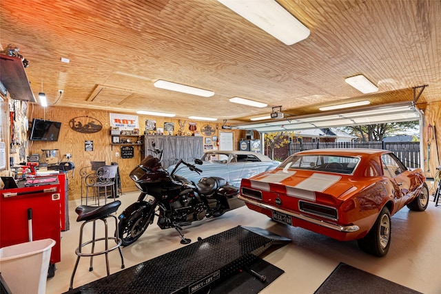 garage with a workshop area, a garage door opener, wood ceiling, and wood walls