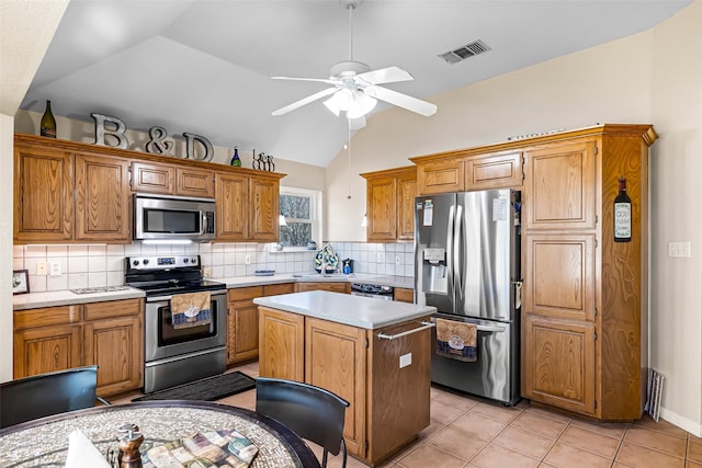 kitchen with ceiling fan, sink, a center island, lofted ceiling, and appliances with stainless steel finishes