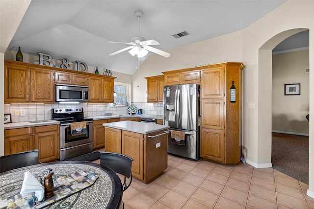 kitchen featuring ceiling fan, a center island, lofted ceiling, light tile patterned floors, and appliances with stainless steel finishes