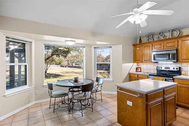 kitchen with light tile patterned floors, stainless steel appliances, a kitchen island, and tasteful backsplash