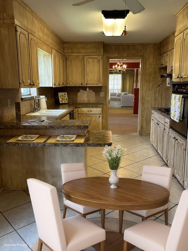 kitchen featuring oven, an inviting chandelier, backsplash, dark countertops, and a peninsula