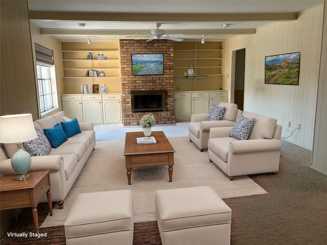 carpeted living room featuring built in features, beam ceiling, ceiling fan, and a fireplace