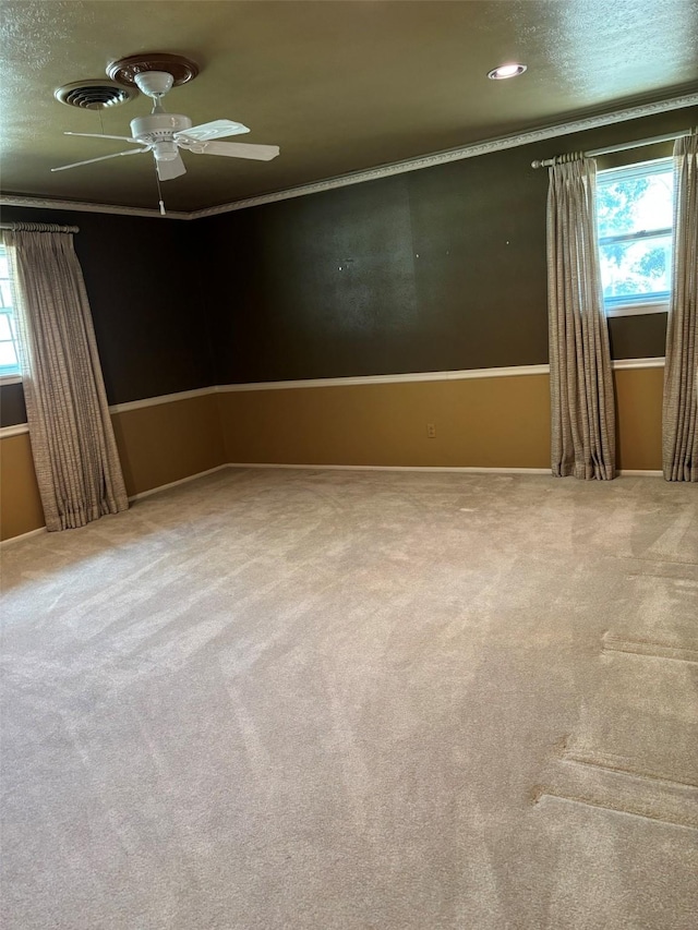 carpeted spare room with ornamental molding and a ceiling fan