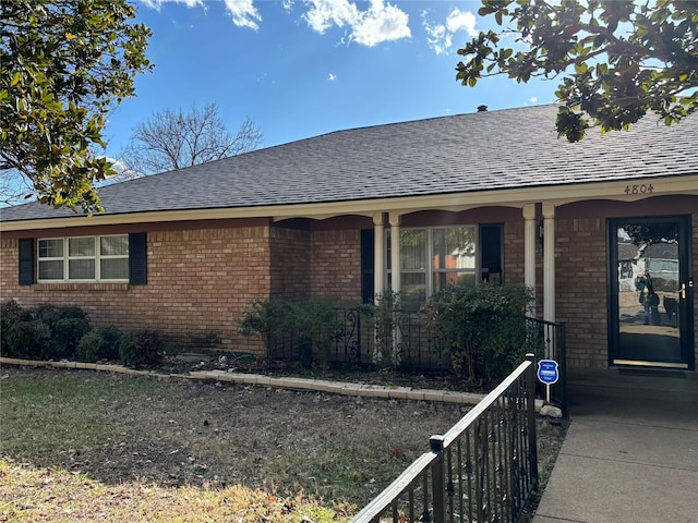 exterior space featuring brick siding, covered porch, and a shingled roof