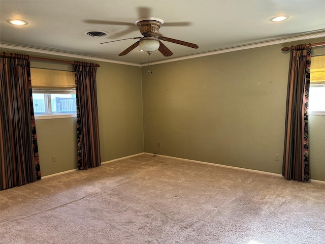 empty room featuring carpet flooring, a ceiling fan, visible vents, and crown molding