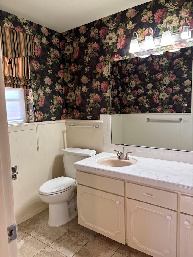bathroom featuring wallpapered walls, a wainscoted wall, toilet, and vanity