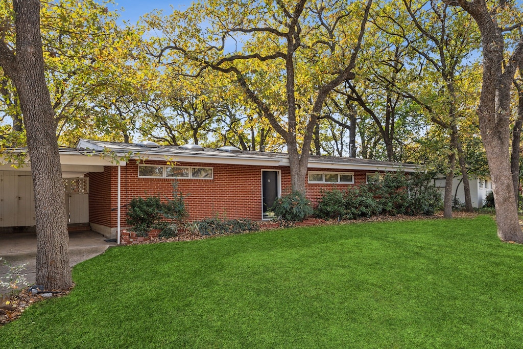 ranch-style house with a carport and a front lawn