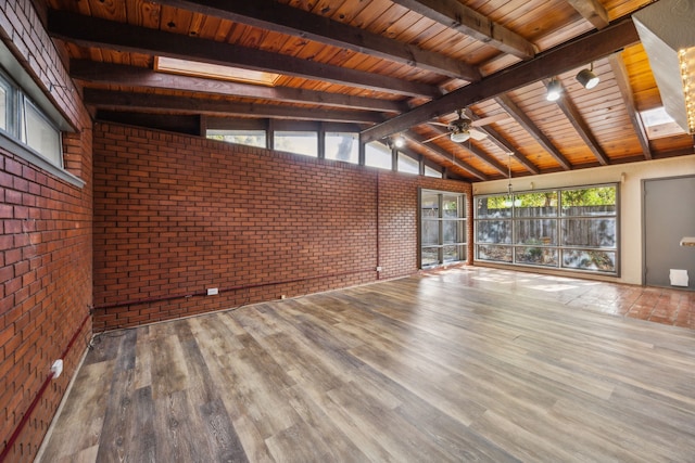 unfurnished living room with vaulted ceiling with beams, brick wall, and hardwood / wood-style flooring