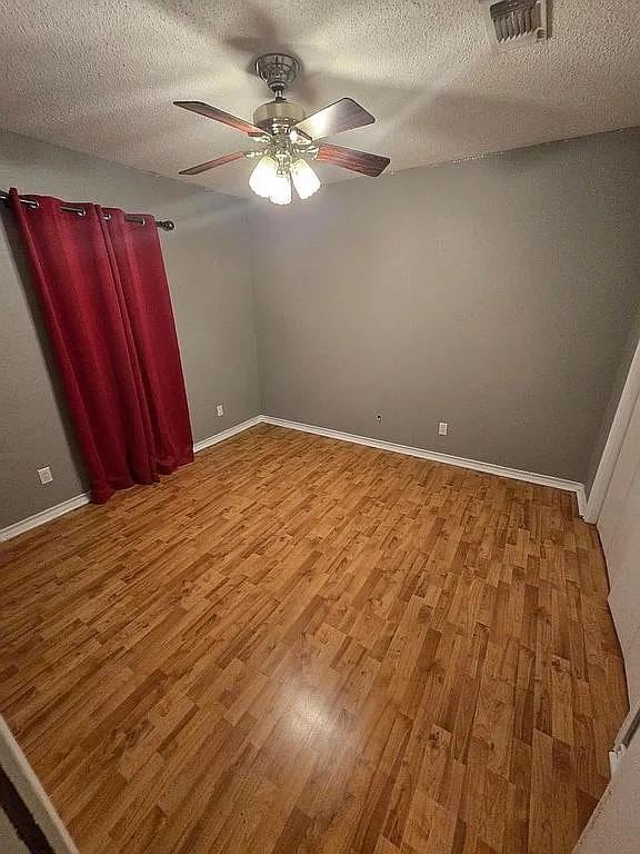 spare room featuring hardwood / wood-style floors, ceiling fan, and a textured ceiling