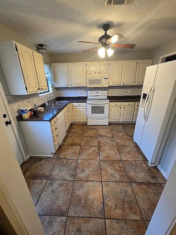 kitchen featuring white appliances, backsplash, sink, ceiling fan, and a textured ceiling