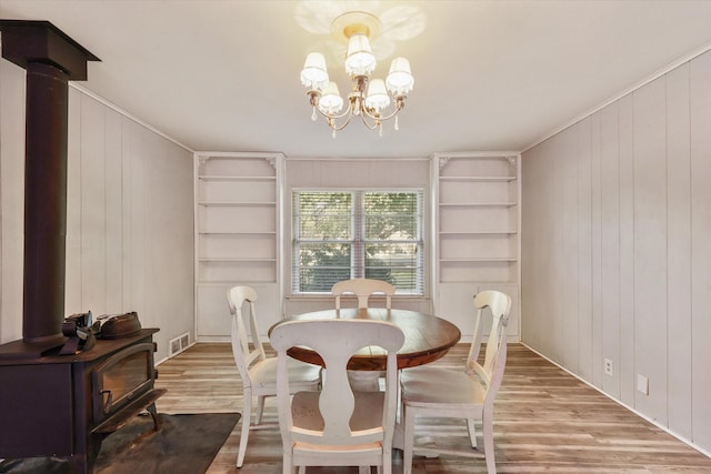 dining area featuring a chandelier, hardwood / wood-style floors, built in features, and a wood stove