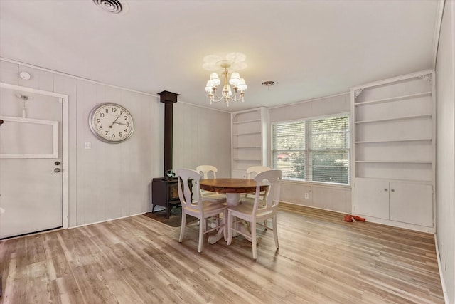 dining space with built in shelves, wood-type flooring, and a chandelier