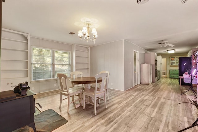 dining room featuring ceiling fan with notable chandelier and light hardwood / wood-style floors