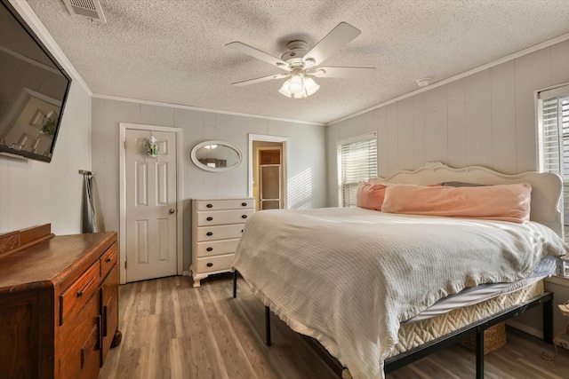 bedroom featuring multiple windows, hardwood / wood-style floors, and ornamental molding