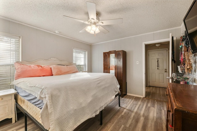 bedroom with wood-type flooring, ceiling fan, a textured ceiling, and crown molding