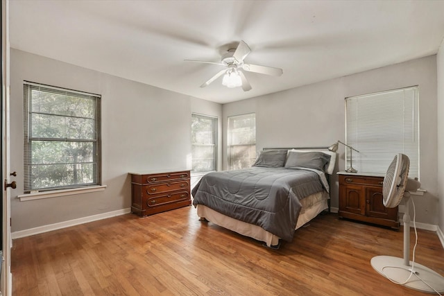 bedroom featuring ceiling fan, multiple windows, and light hardwood / wood-style flooring