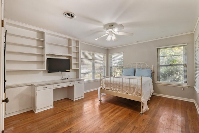 bedroom featuring hardwood / wood-style flooring, ceiling fan, crown molding, and built in desk