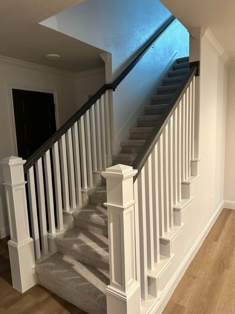 staircase featuring hardwood / wood-style floors and crown molding