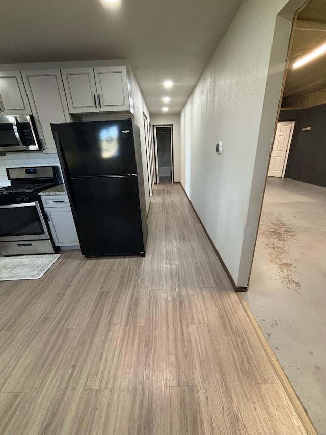 kitchen with stainless steel appliances, light hardwood / wood-style floors, and backsplash