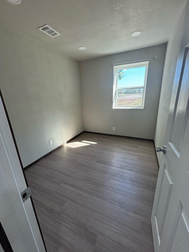 spare room featuring light hardwood / wood-style floors and a textured ceiling