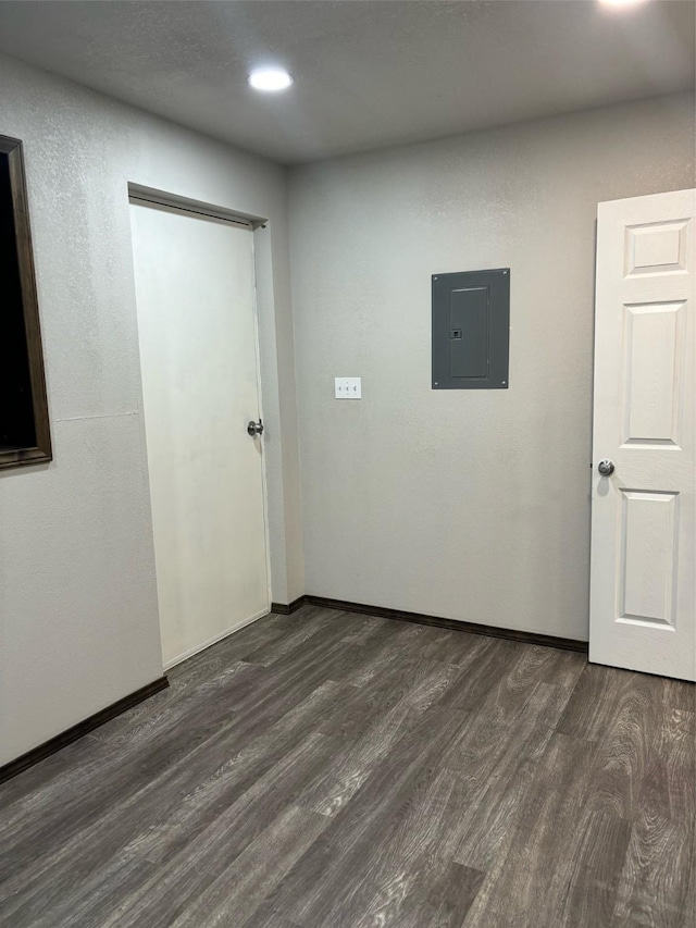 unfurnished room featuring electric panel and dark hardwood / wood-style flooring