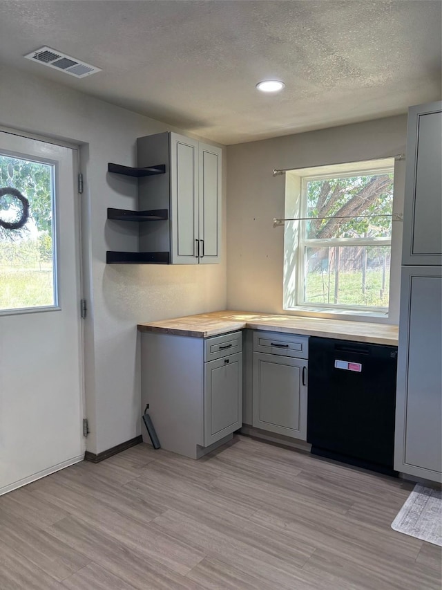 kitchen with gray cabinets, wooden counters, black dishwasher, light hardwood / wood-style floors, and a textured ceiling