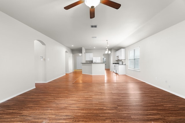 unfurnished living room featuring dark wood-type flooring and ceiling fan with notable chandelier