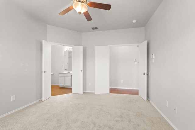 unfurnished bedroom featuring ceiling fan, light colored carpet, and connected bathroom