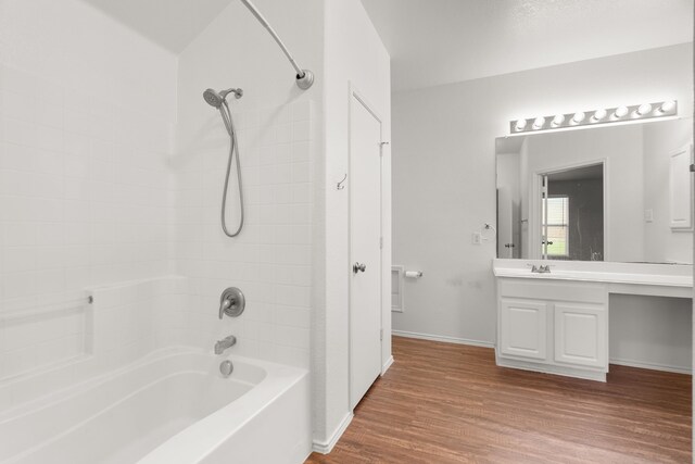 bathroom with hardwood / wood-style flooring, tiled shower / bath combo, and vanity