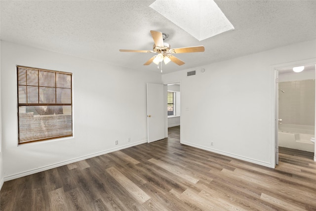 empty room with hardwood / wood-style floors, a textured ceiling, and a skylight