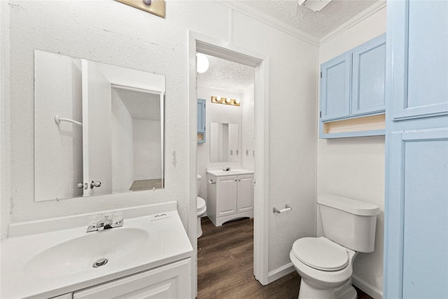 bathroom with hardwood / wood-style floors, a textured ceiling, toilet, vanity, and ornamental molding