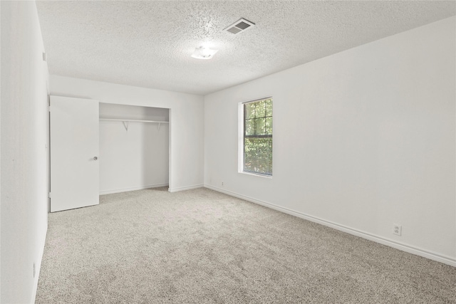 unfurnished bedroom with a closet, light colored carpet, and a textured ceiling