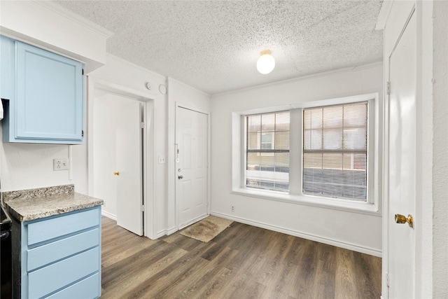 kitchen featuring ornamental molding, dark wood-type flooring, a textured ceiling, and blue cabinets