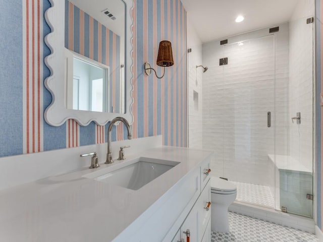 bathroom with tile patterned floors, vanity, toilet, and a shower with door