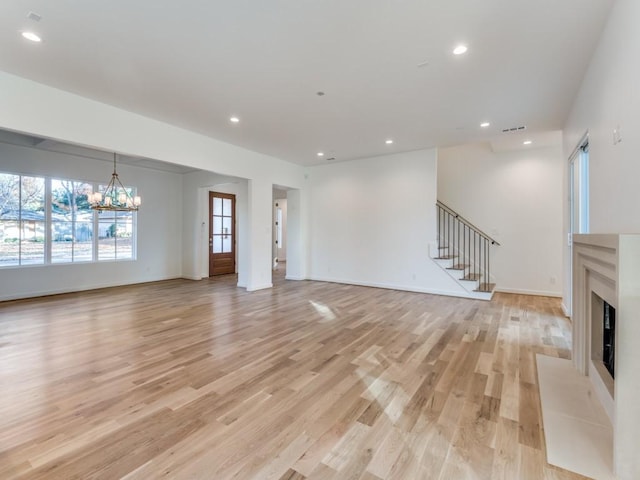 unfurnished living room with a fireplace, light hardwood / wood-style flooring, and a notable chandelier