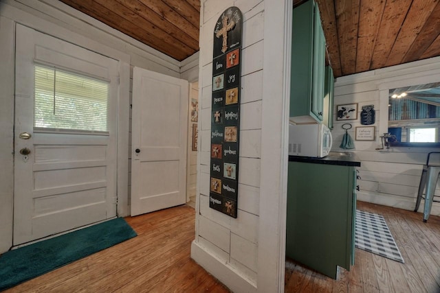 entryway featuring lofted ceiling, light wood-type flooring, wooden ceiling, and wooden walls