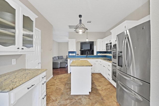 kitchen featuring pendant lighting, white cabinets, sink, appliances with stainless steel finishes, and a kitchen island