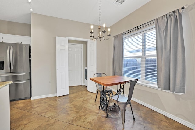 tiled dining room featuring plenty of natural light and a chandelier