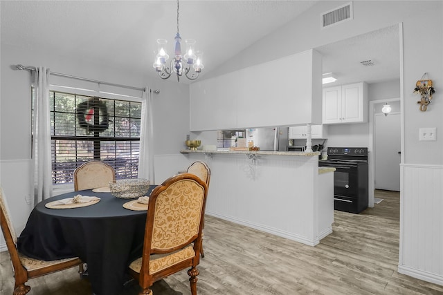 dining room with an inviting chandelier, light hardwood / wood-style flooring, and vaulted ceiling