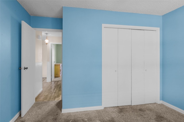 unfurnished bedroom featuring carpet floors, a textured ceiling, and a closet