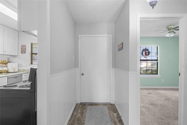 corridor with light hardwood / wood-style floors and a textured ceiling