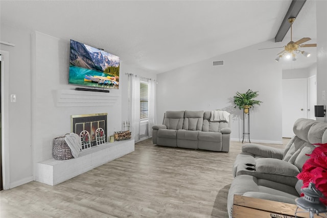 living room featuring vaulted ceiling with beams, ceiling fan, light hardwood / wood-style floors, and a brick fireplace