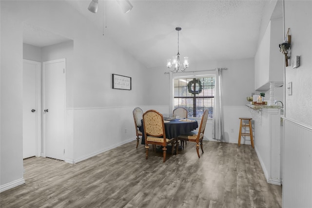 dining area with ceiling fan with notable chandelier, hardwood / wood-style floors, a textured ceiling, and lofted ceiling