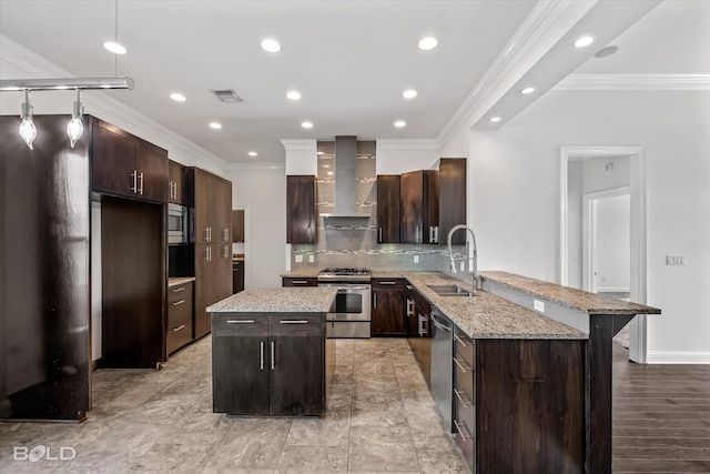 kitchen featuring dark brown cabinetry, stainless steel appliances, wall chimney range hood, sink, and a center island