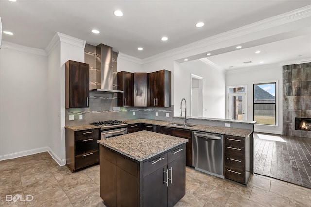 kitchen featuring a center island, wall chimney range hood, sink, dark brown cabinets, and stainless steel appliances