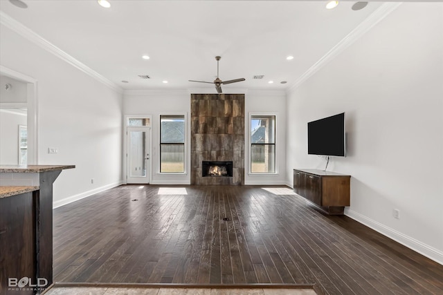 unfurnished living room with a tiled fireplace, crown molding, dark hardwood / wood-style floors, and ceiling fan