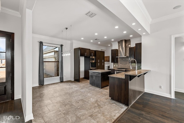 kitchen with kitchen peninsula, light stone counters, wall chimney exhaust hood, a kitchen island, and a breakfast bar area